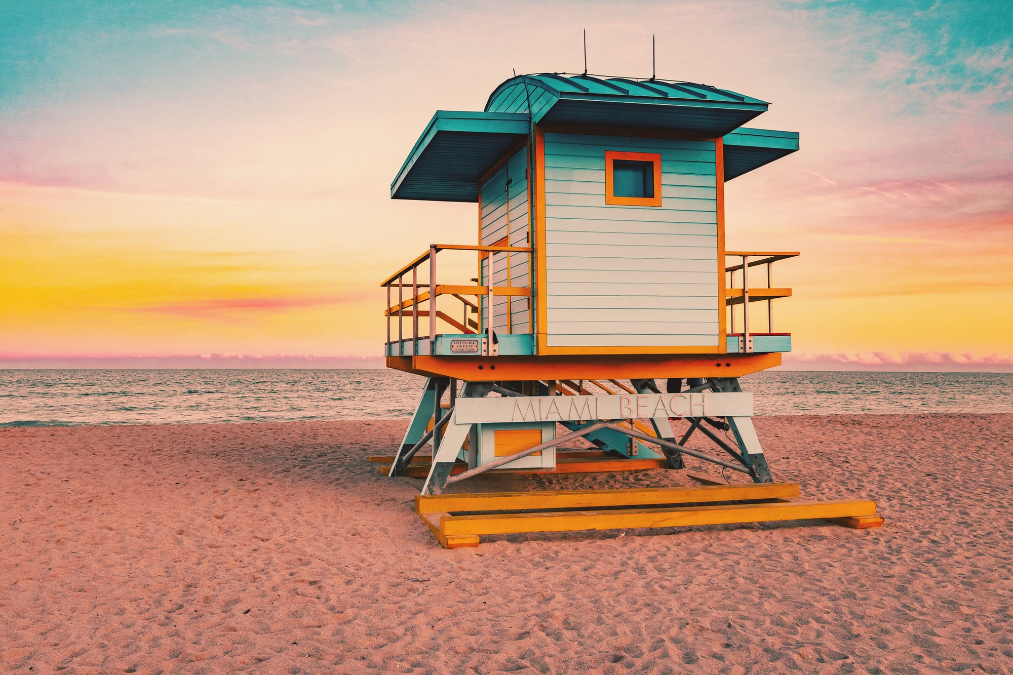 Colorful Miami Beach lifeguard tower with stunning sunset sky and empty beach.