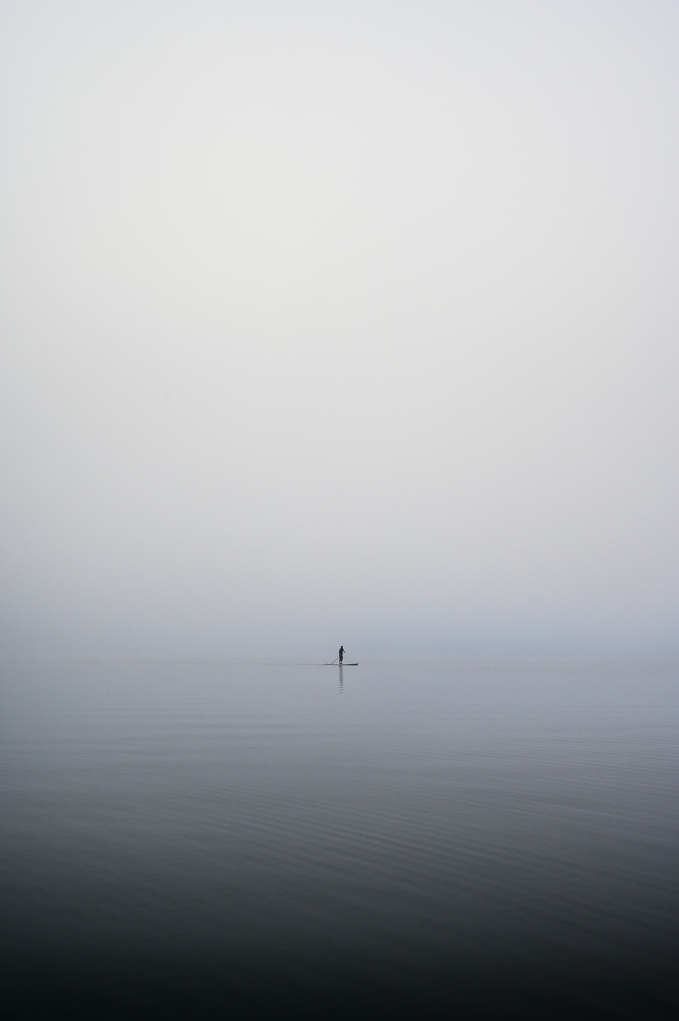 SUP Stand up paddling on mountain lake in early morning